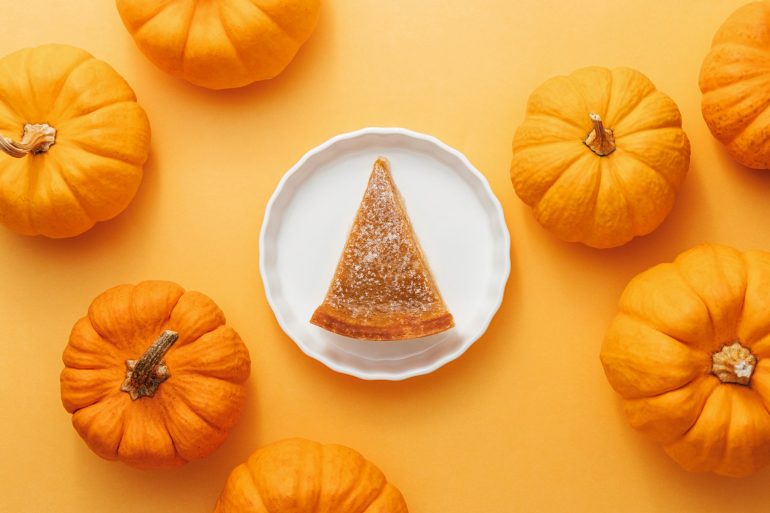 slice on pumpkin pie flat lay on orange pumpkin background