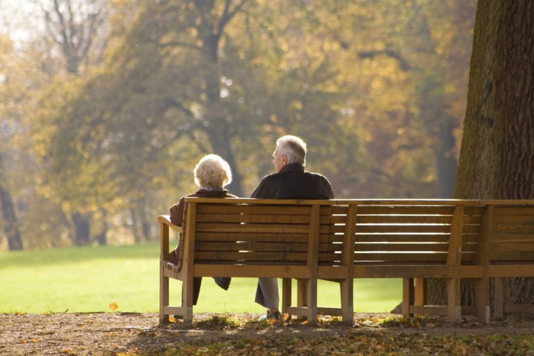 Picturesque couple sitting on a park bench in the middle of fall | MakeItGrateful.com