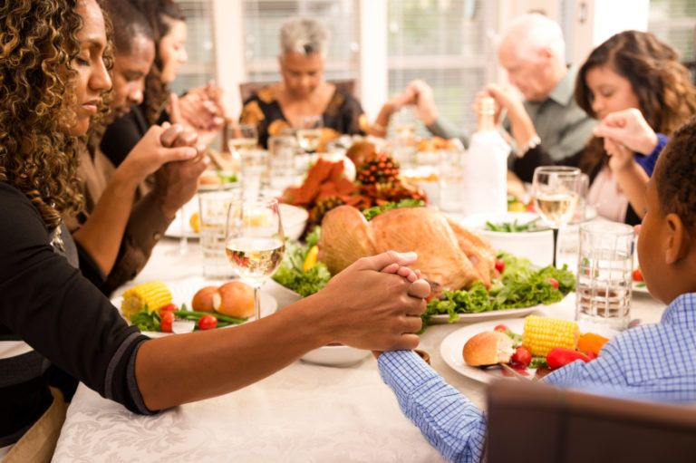 Family praying around the Thanksgiving table | MakeItGrateful.com