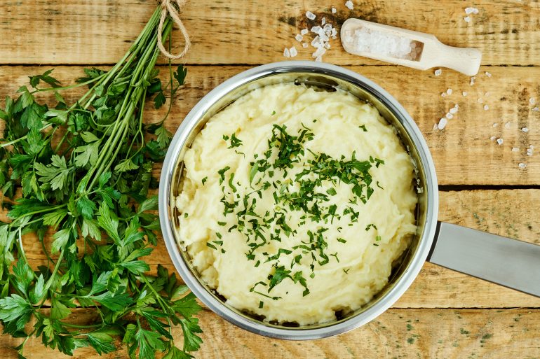 creamy puree sprinkled with parsley in a silver pot on a wooden table