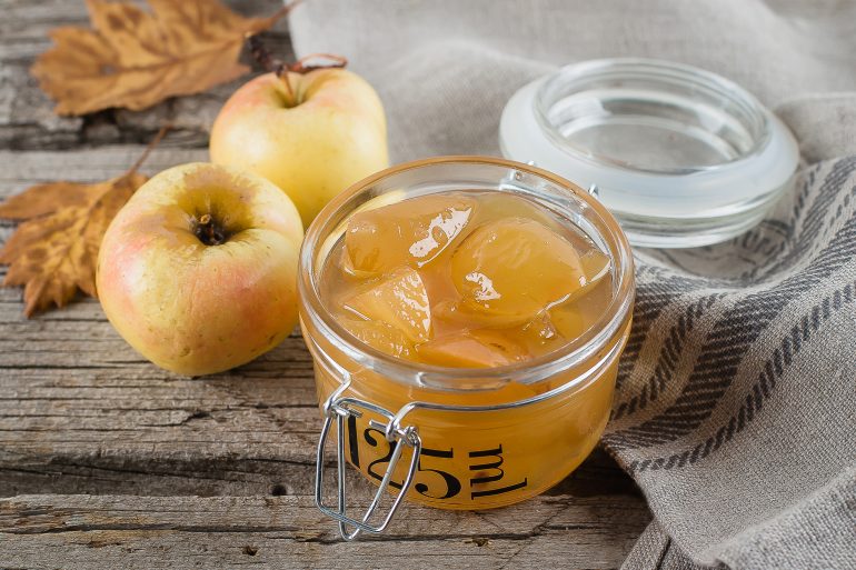 Homemade apple jam or sauce in jar on table. Wooden rustic background, close up