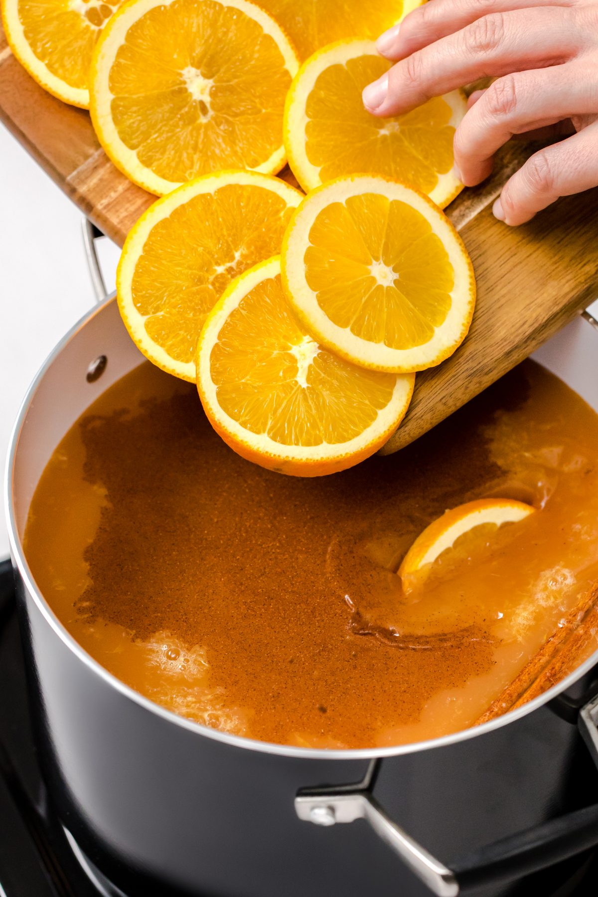 Adding oranges to the wassail holiday punch