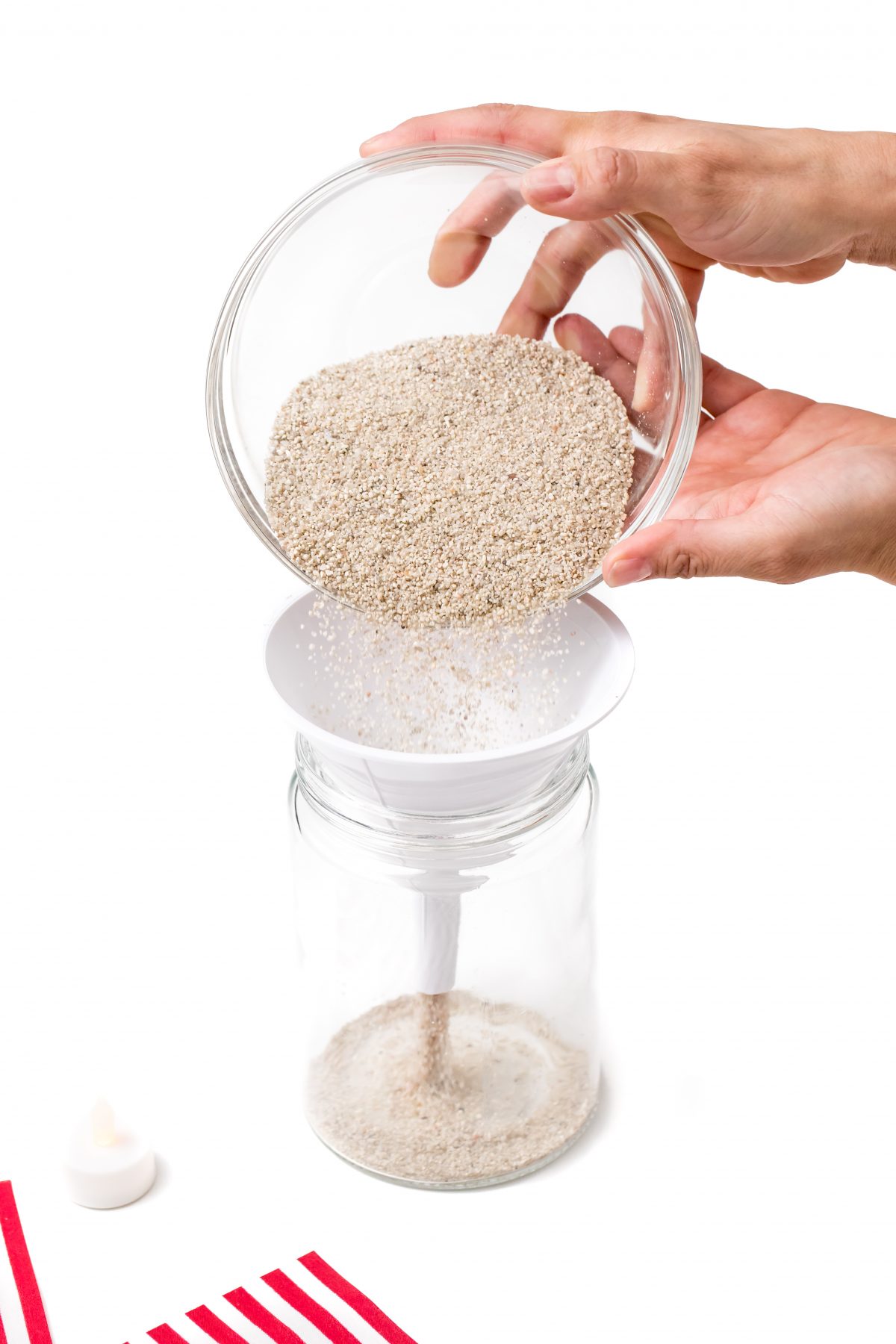 Using a funnel, pour sand into the mason jar