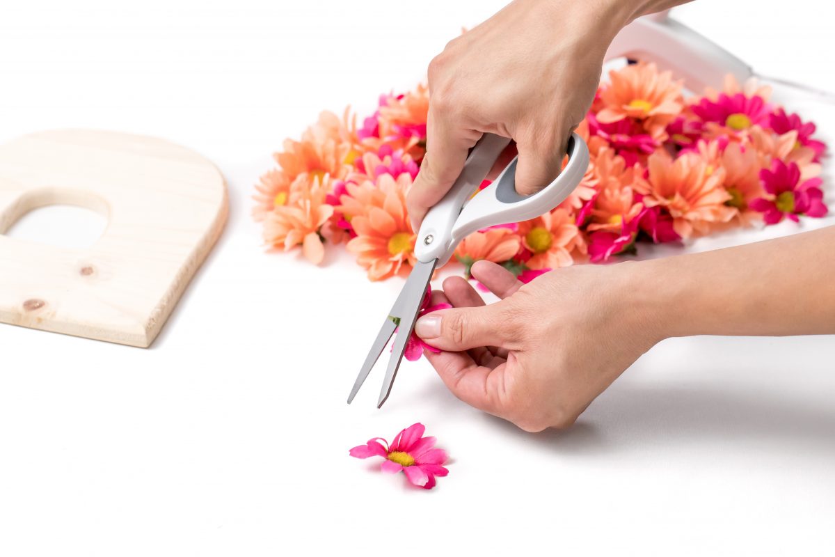 Cut excess stem from flower with scissors for floral letter craft