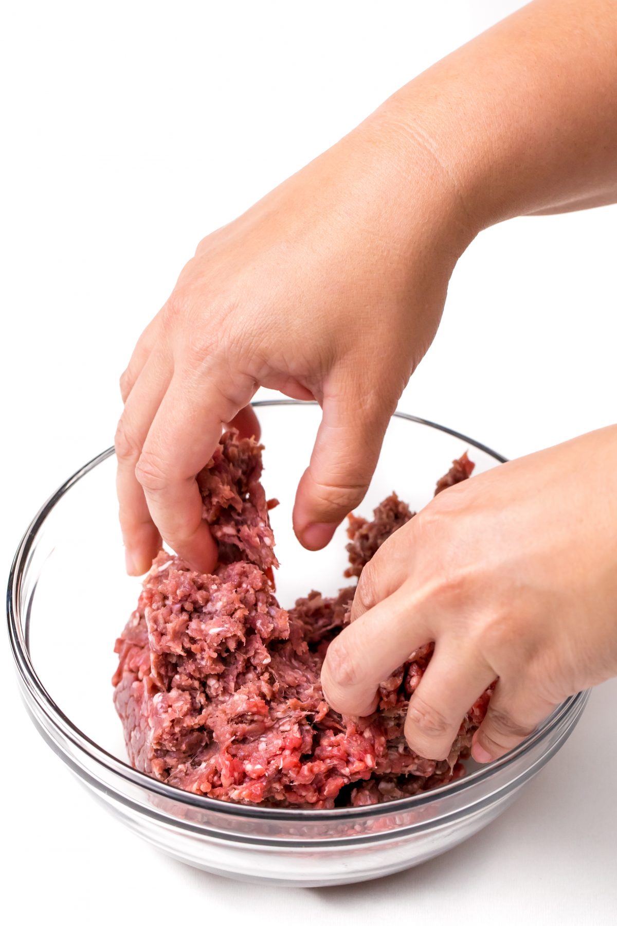 Oven baked burgers mixing raw beef in bowl by hand