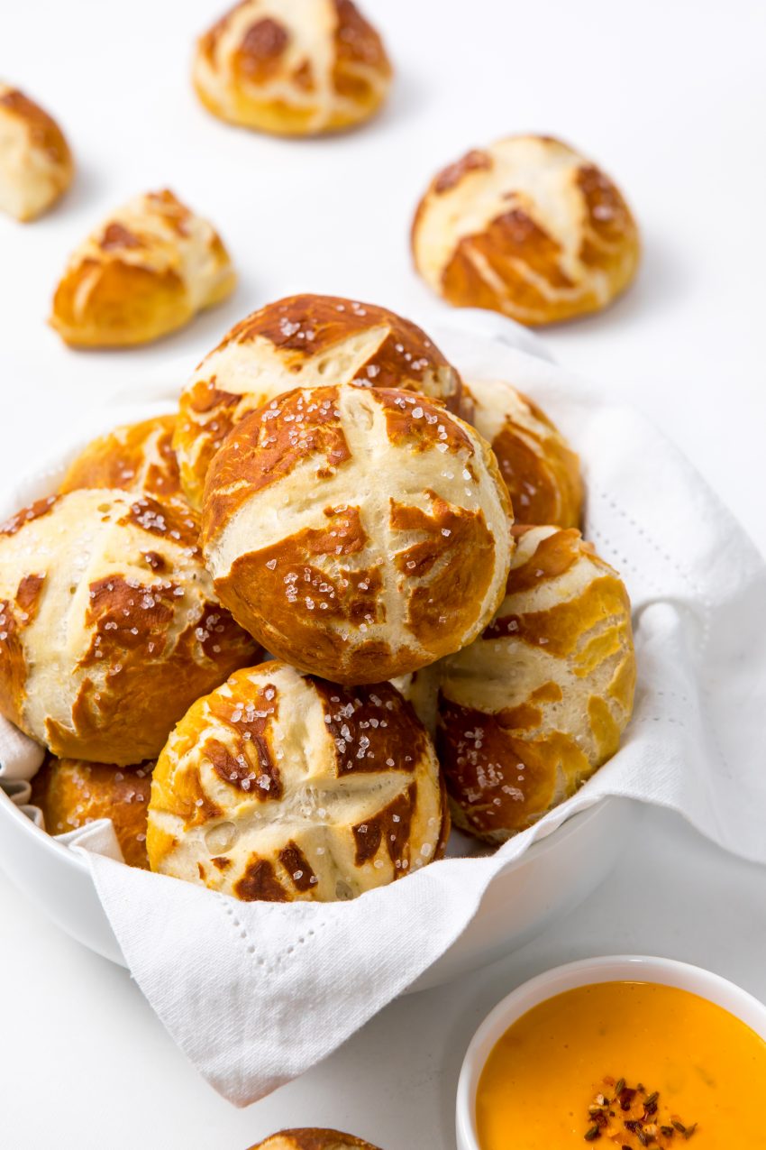5D4B5910 - Easy Pretzel Rolls - a bread basket filled with preztel rolls surrounded by cheese and pretzels