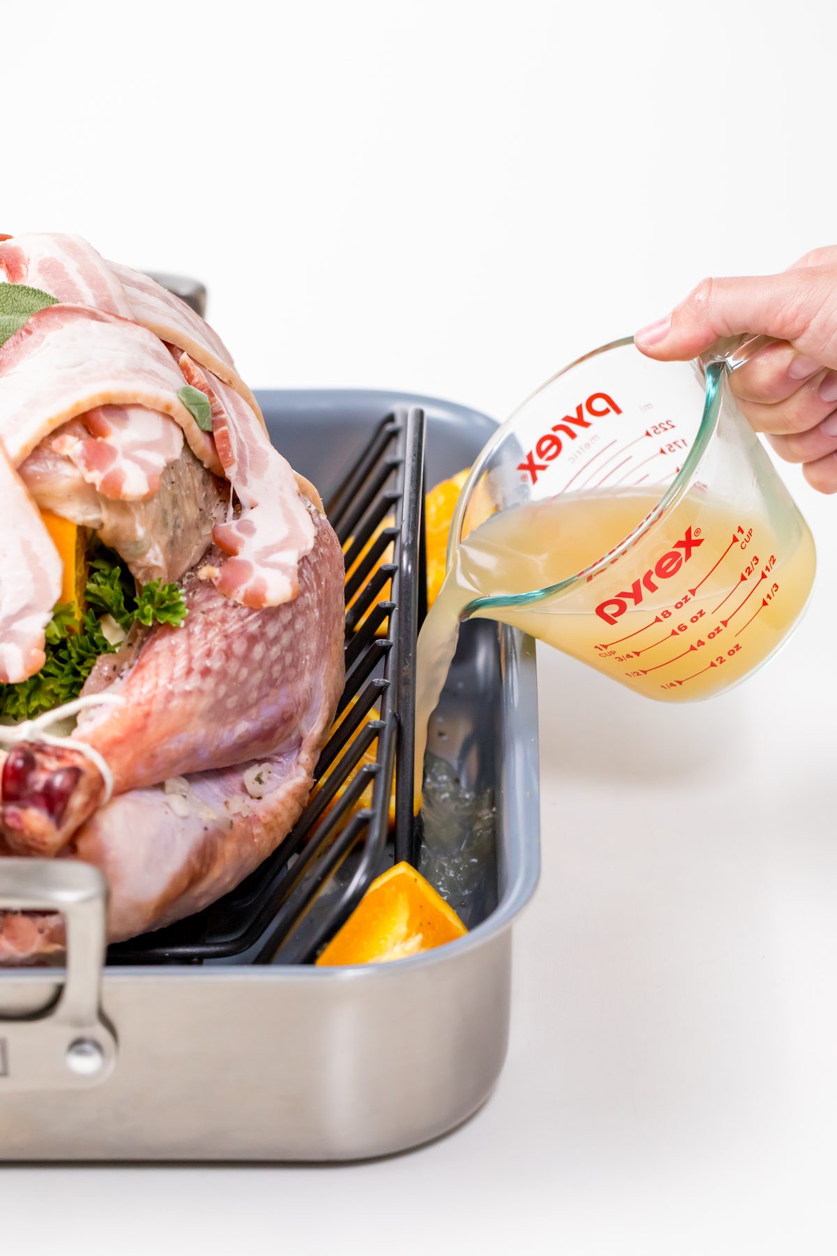 5D4B9108 - Bacon Wrapped Turkey - pouring chicken broth in bottom of pan