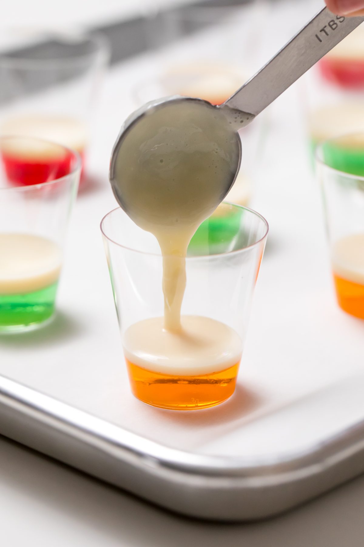 Layer Jell-O and sweetened condensed milk gelatin in shot glasses