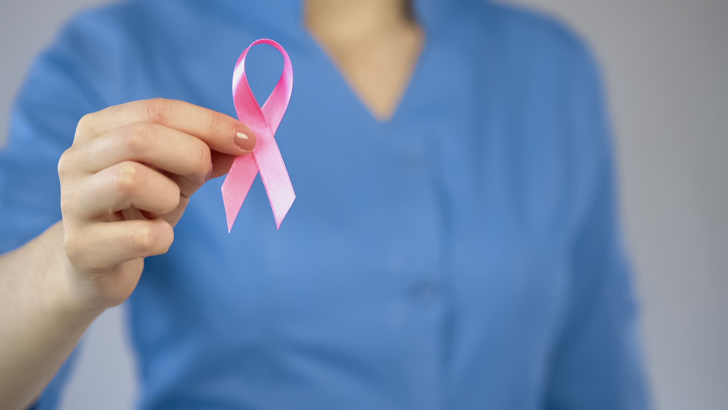 Breast cancer survivors nurse showing pink ribbon closeup, breast anticancer campaign, examination