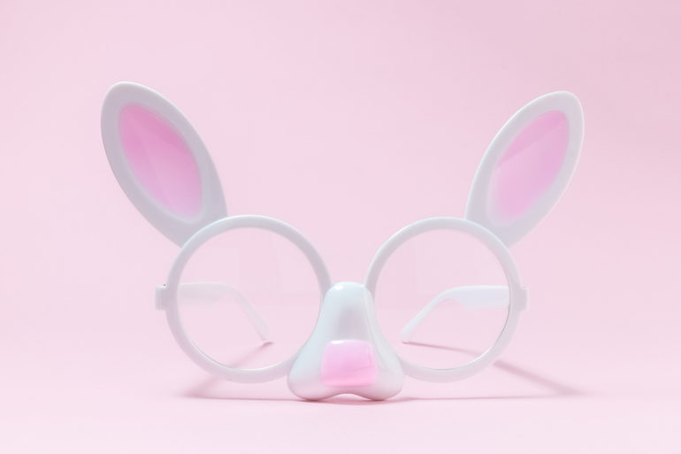 Eyeglasses in form of bunny face against pink rose pastel background minimalistic easter concept