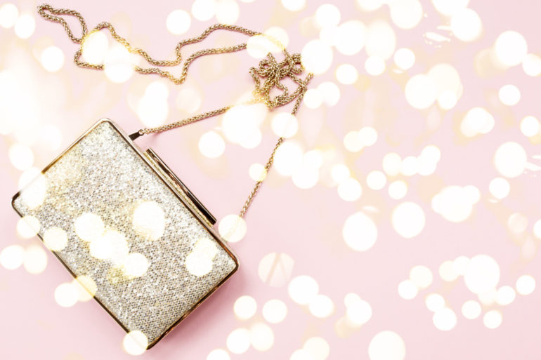 Festive evening golden clutch on pink. Holiday and celebration background. Luxury accessories and party concept