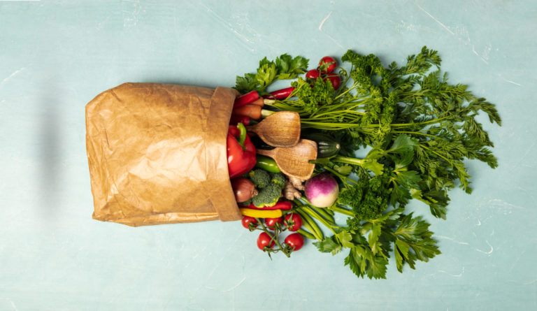 Grocery shopping concept. Different food in paper bag on colorful background