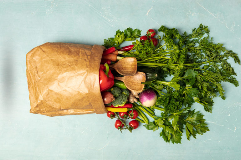 Grocery shopping concept. Different food in paper bag on colorful background