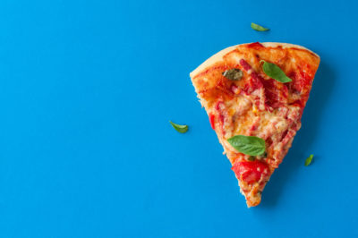One piece of salami pizza on blue background. Top view and copy