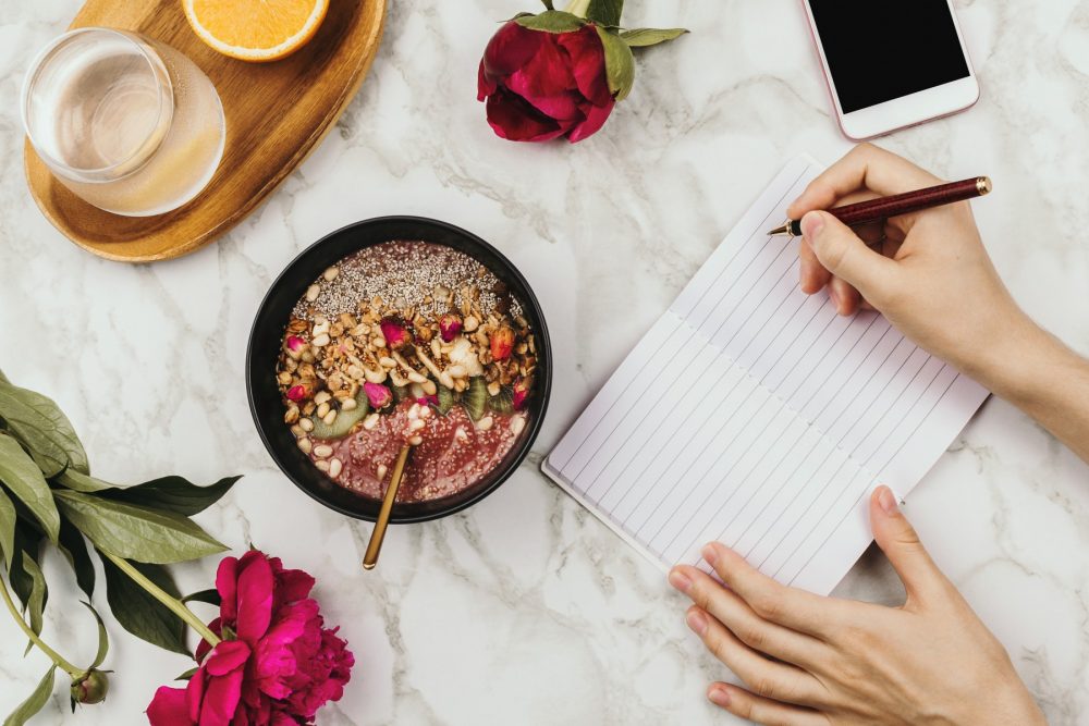 journal with acai bowl and flowers